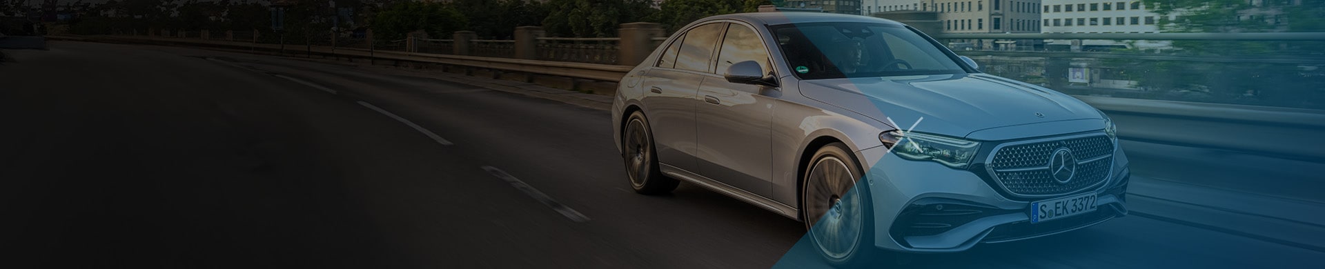 Luxury sedan driving through a city at sunset.