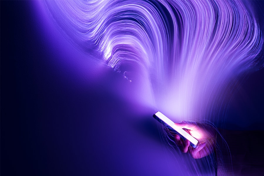 Person holding a smartphone against a purple background.